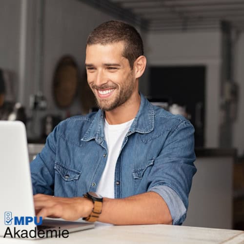 Lächelnder Mann bei der Online MPU-Vorbereitung am Laptop